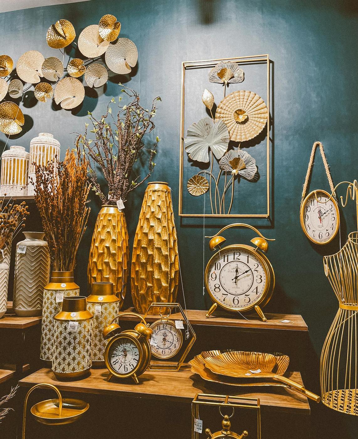 Deep teal wall with golden decorative objects and framed metallic floral art