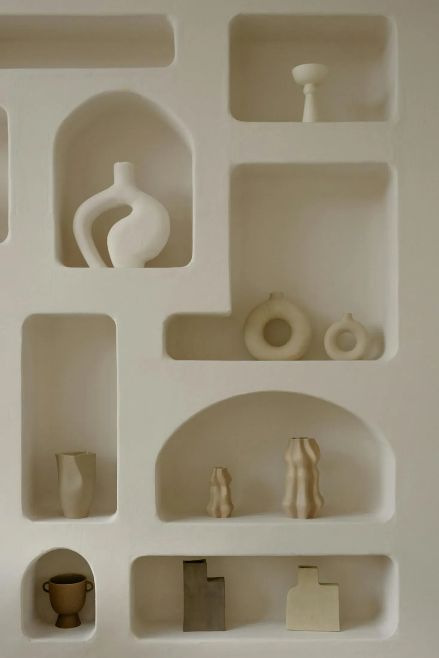 Minimal wall shelf with cream ceramic vases and rounded sculptural shapes