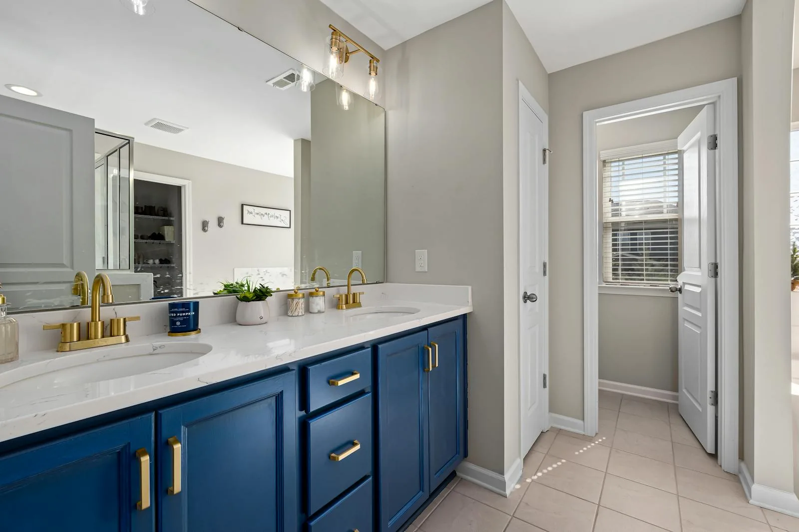 Bathroom with blue vanity, warm brass hardware, and light neutral walls