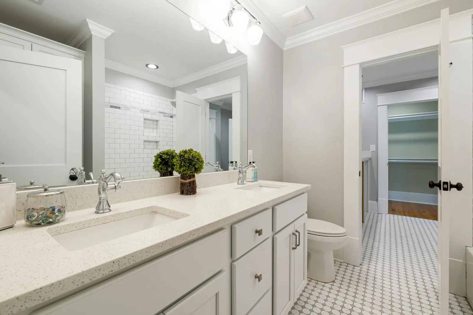 Bright white bathroom vanity with one small plant beside the mirror