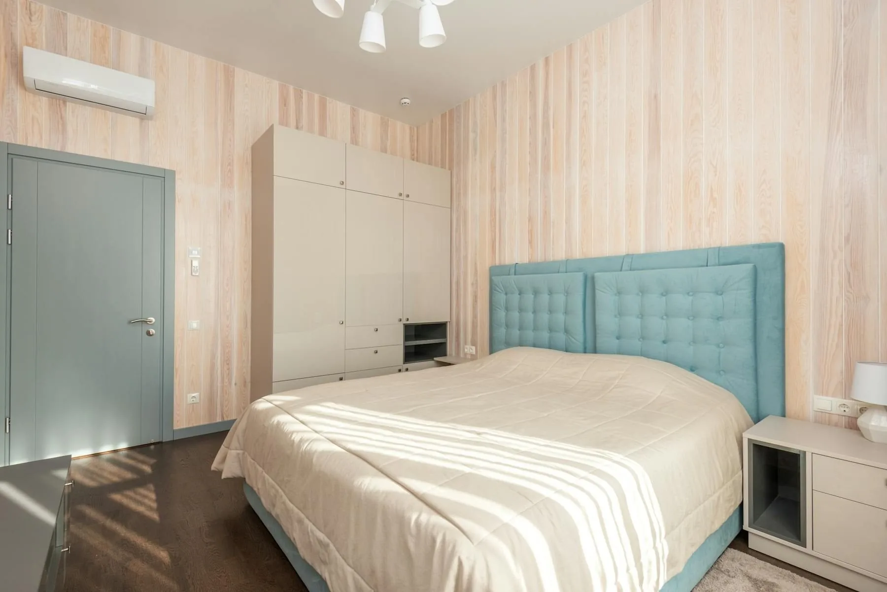 Bedroom with upholstered headboard, soft bedding, and a supportive wall behind the bed
