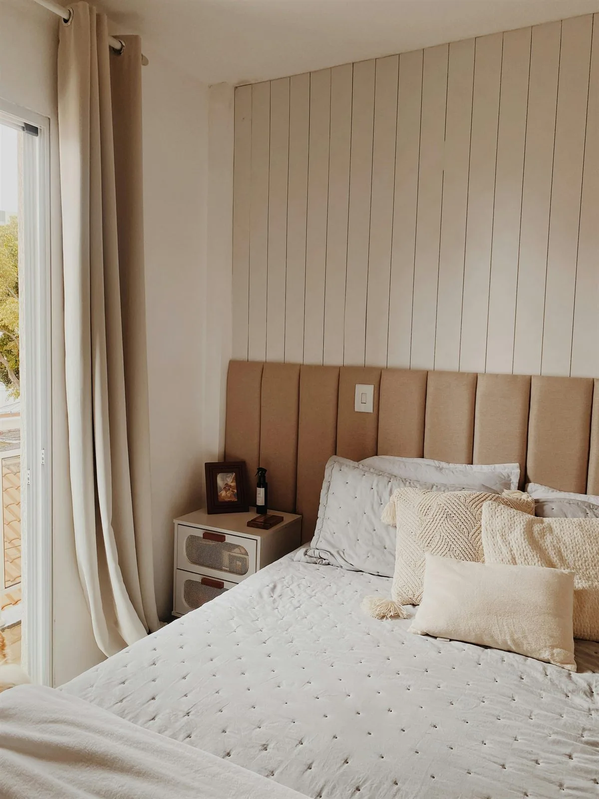 Soft bedroom with upholstered bed, creamy bedding, and a calmer more grounded headboard wall