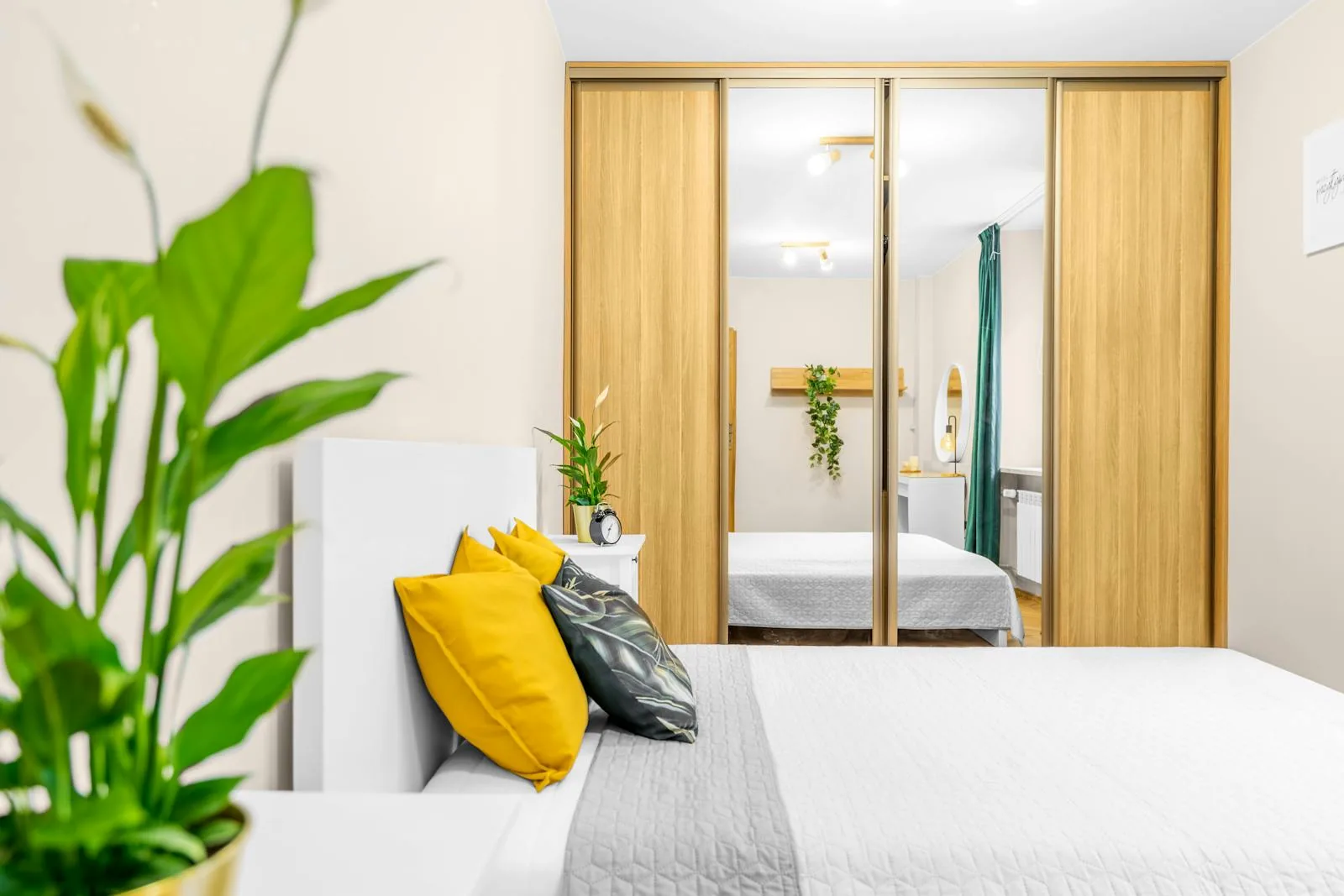 Bedroom with a leafy plant near the bed and soft natural light