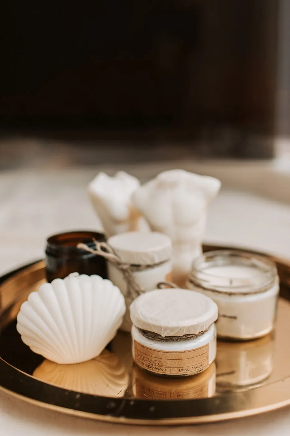 Neutral candles and small holders arranged on a reflective gold tray