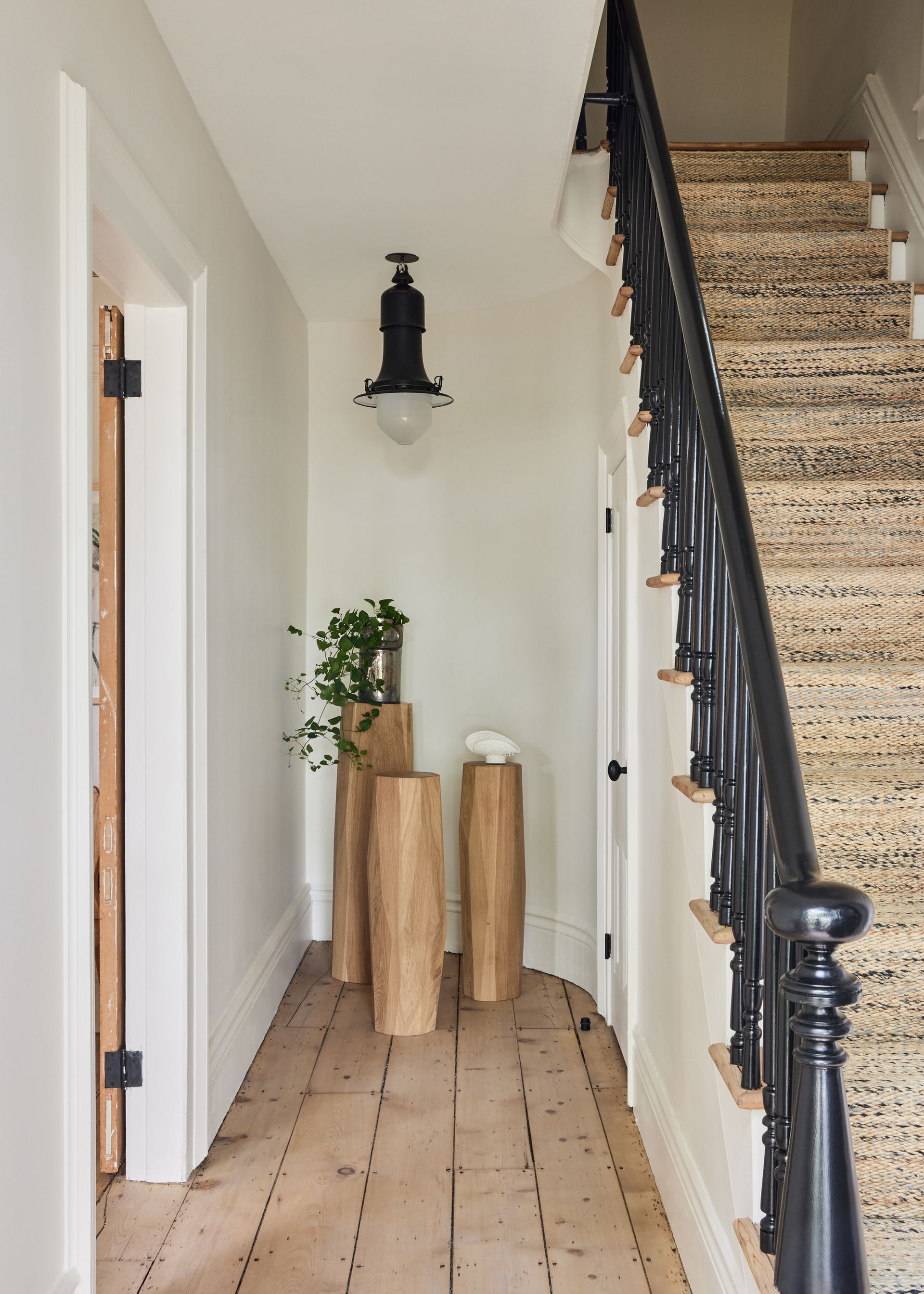 Bright entry hall with open floor space, soft daylight, and simple wood pedestals