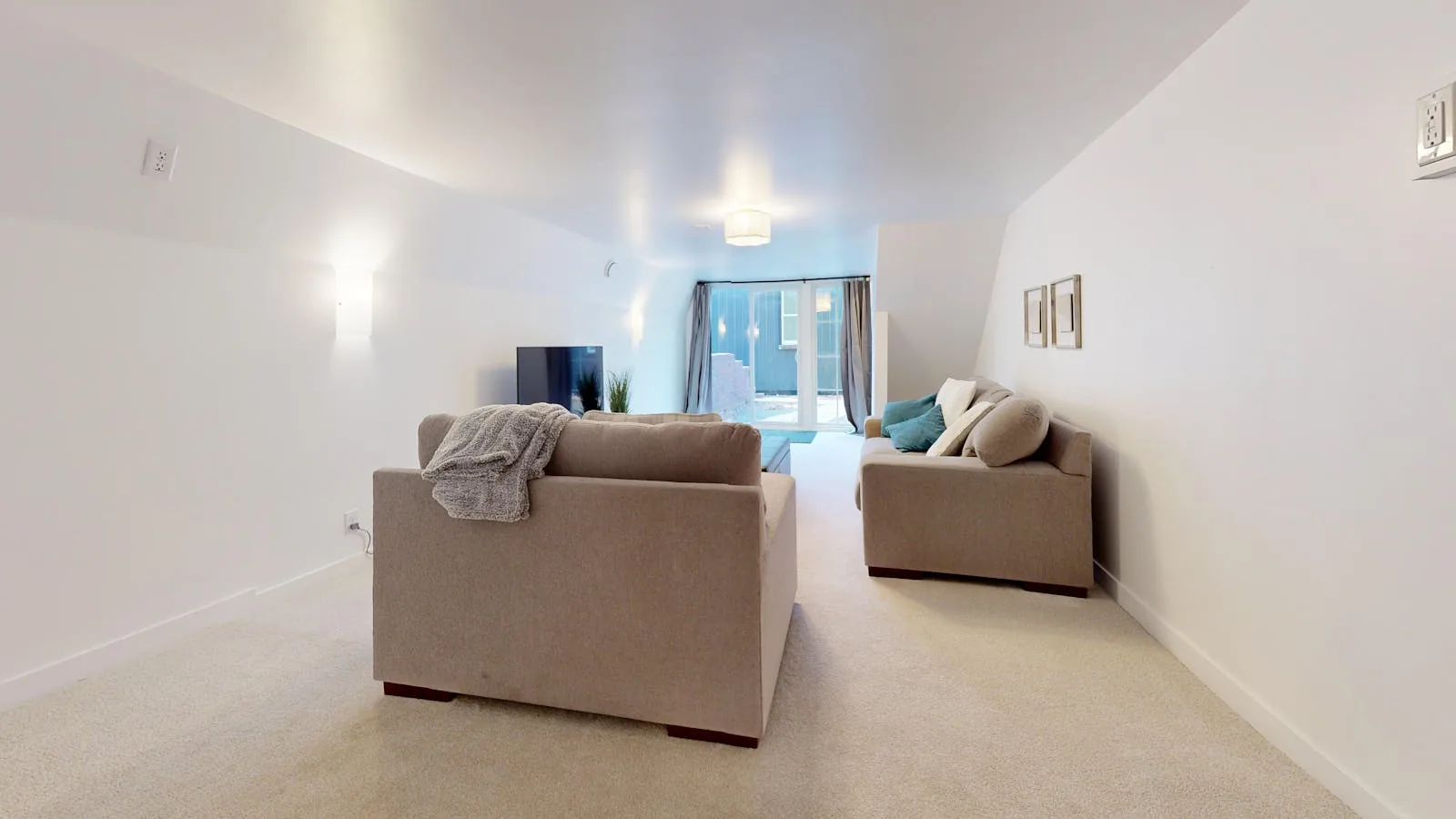 Neutral living room with open floor space, simple seating, and a clear path to the light