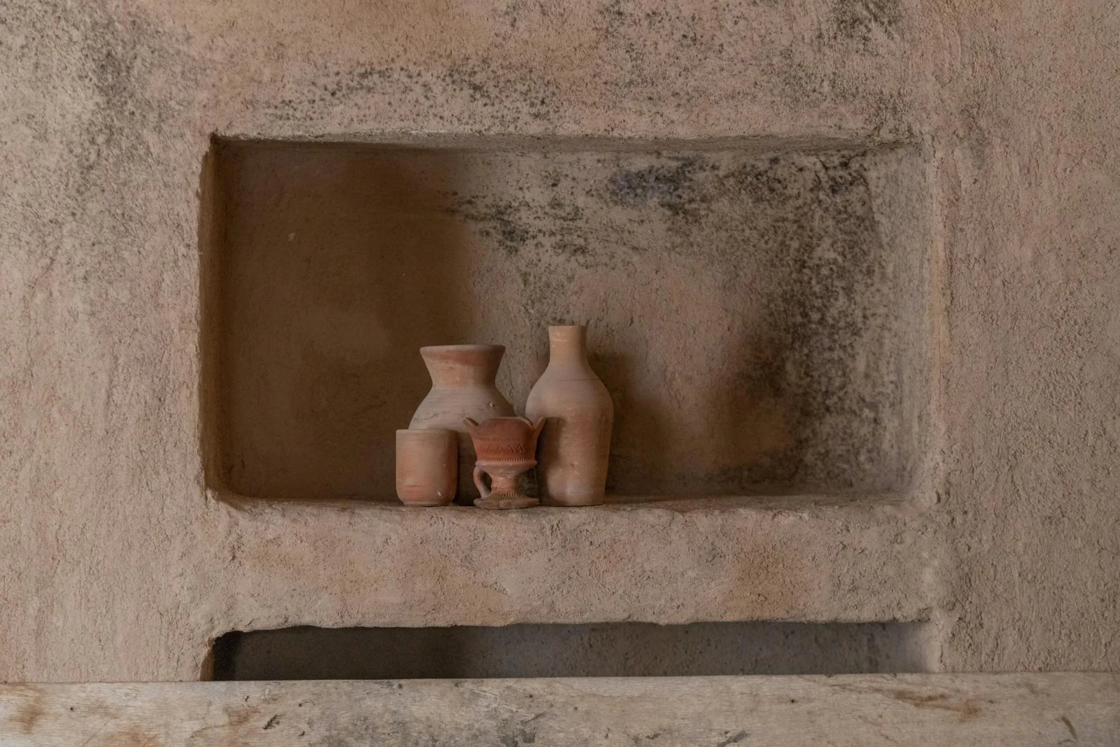 Small clay pottery pieces in a warm textured wall niche