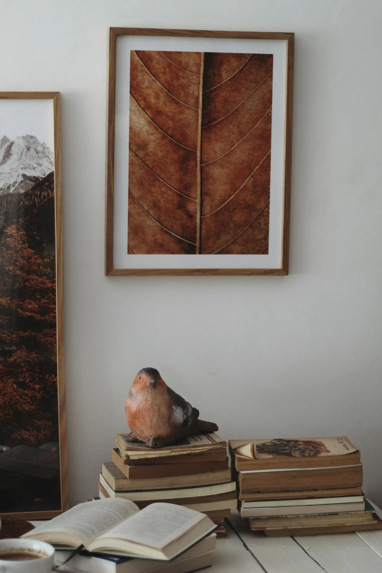 Open book with stacked books and framed art in a warm calm reading corner