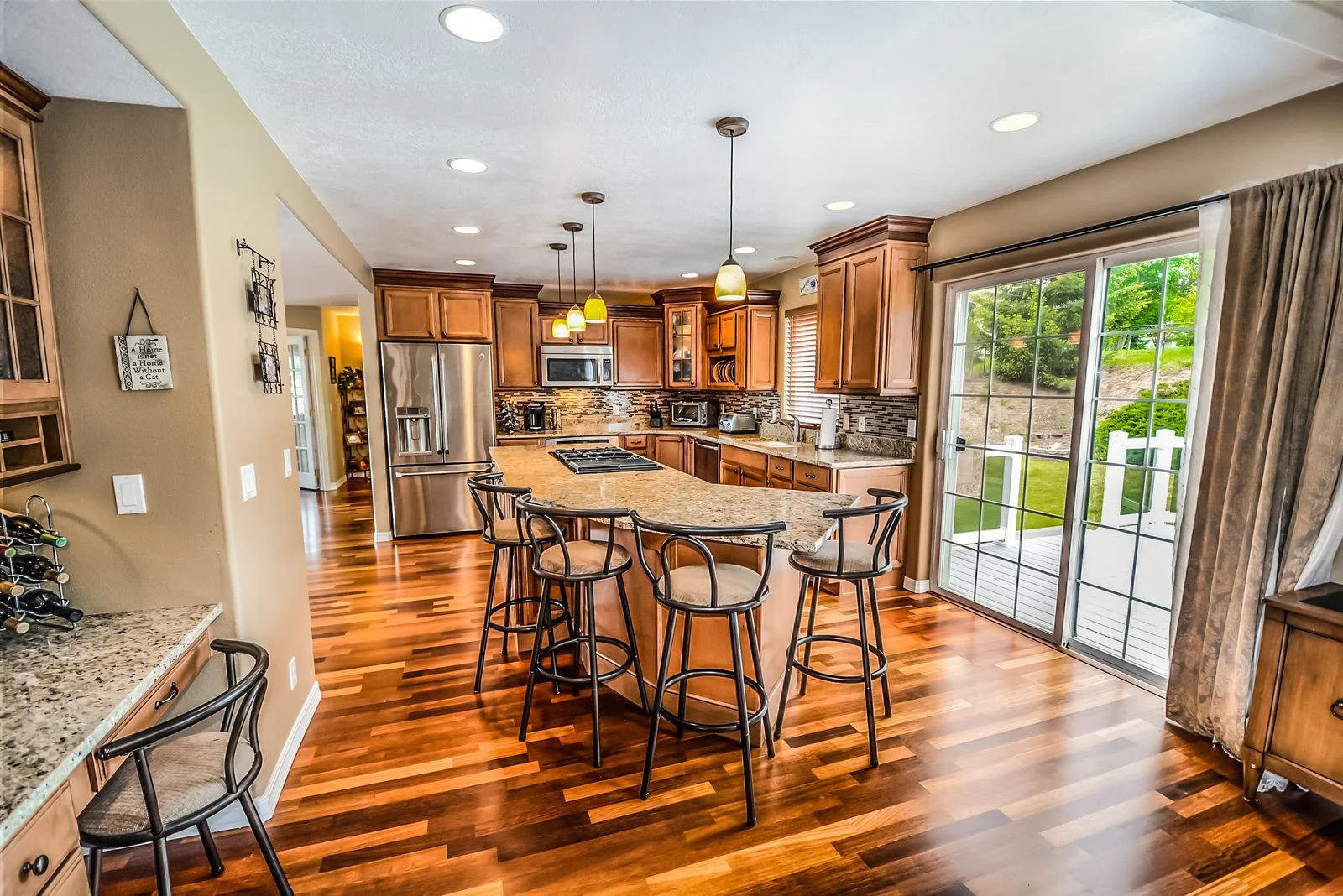 A kitchen with an island cooktop, bar stools, fitted cabinets and a sliding exterior door