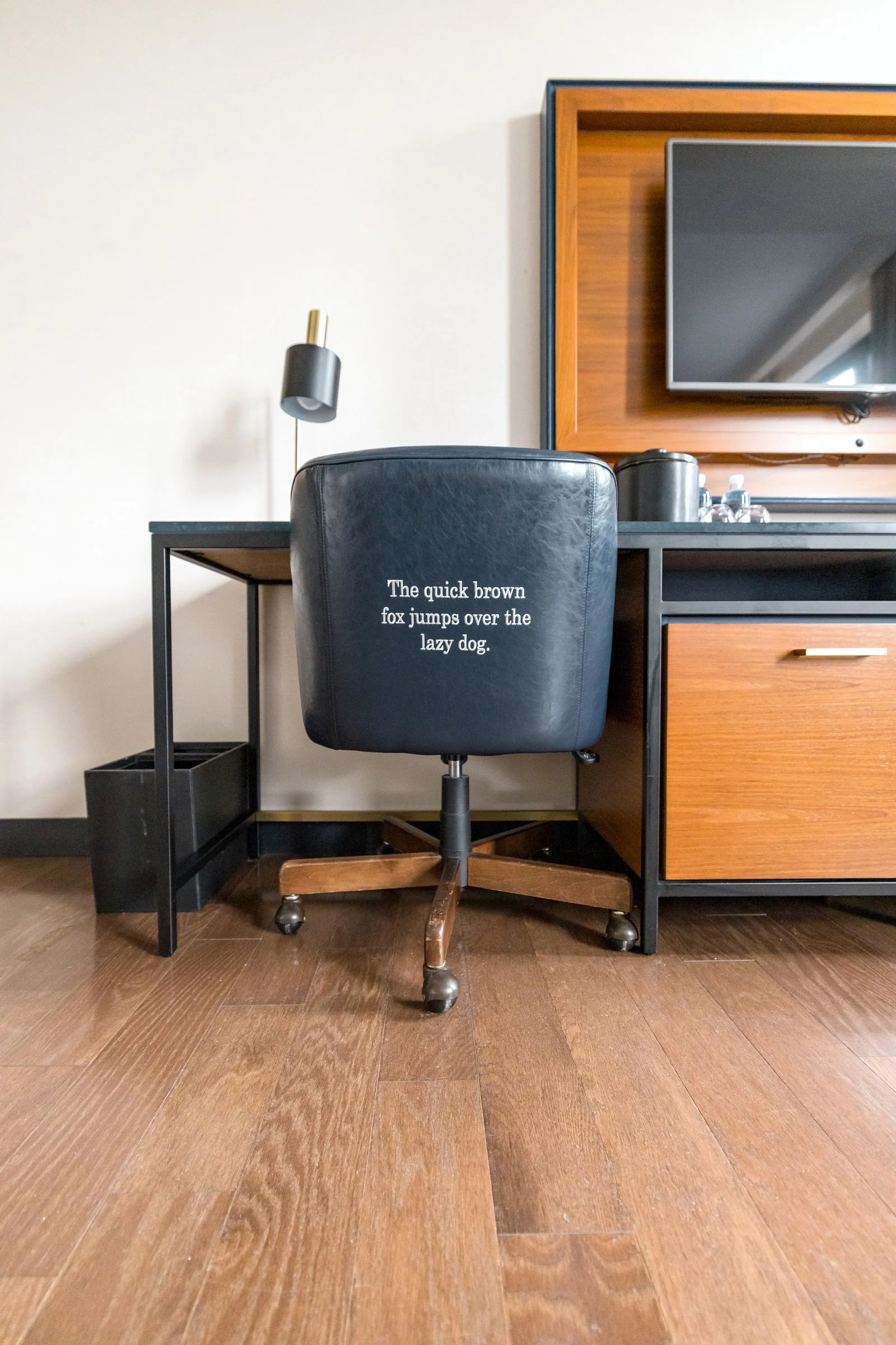 A rolling office chair tucked beneath a compact desk with drawers beside it