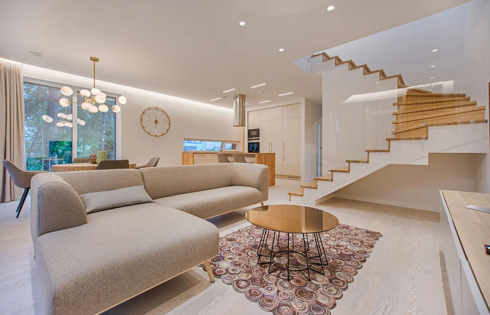 An open-plan living room with a freestanding sectional sofa, coffee table and staircase
