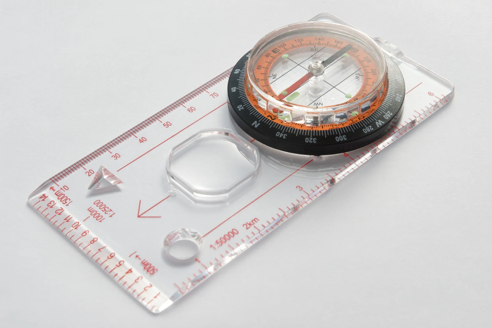 Close-up of a transparent baseplate compass with a rotating degree scale and a red-and-black magnetic needle