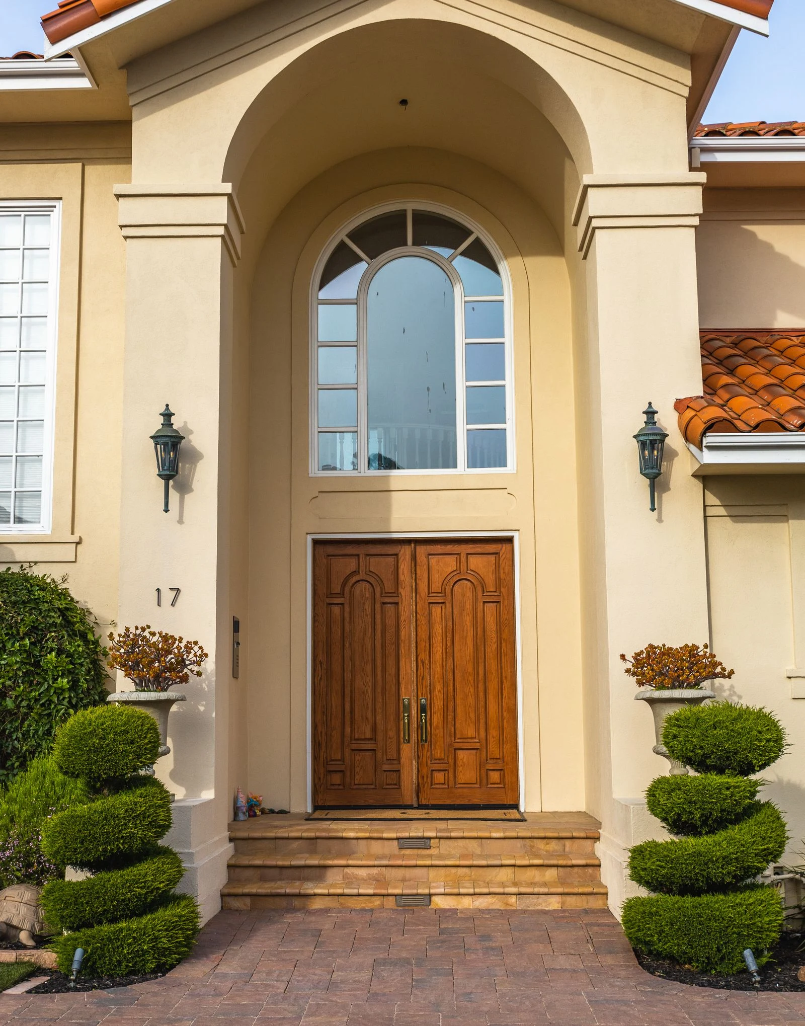 Recessed double wooden entrance doors within a larger stucco facade, with steps leading to the doorway