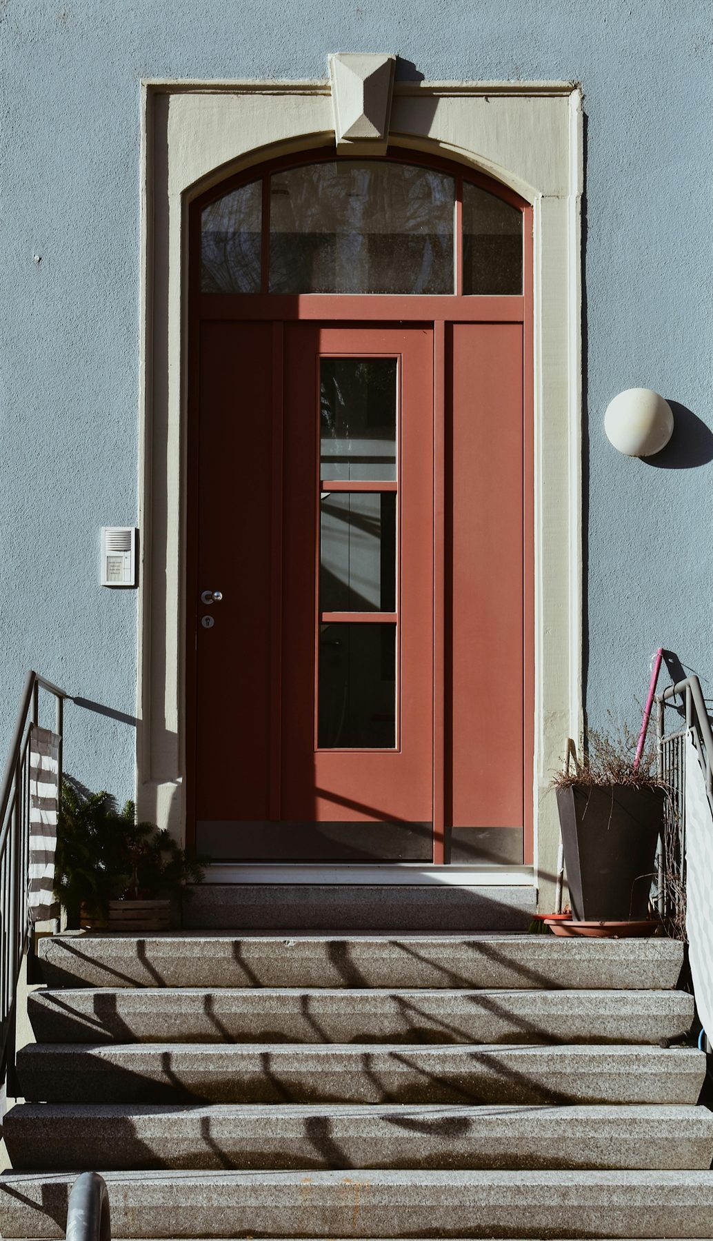 Terracotta-toned front door with steps and a light exterior wall