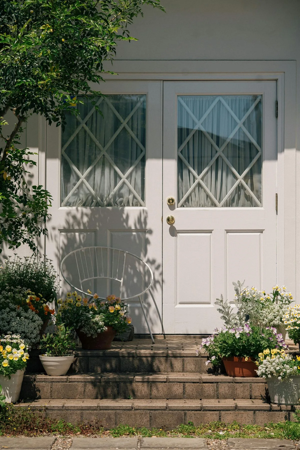 Light front door with flowers on the steps and a clean symmetrical threshold