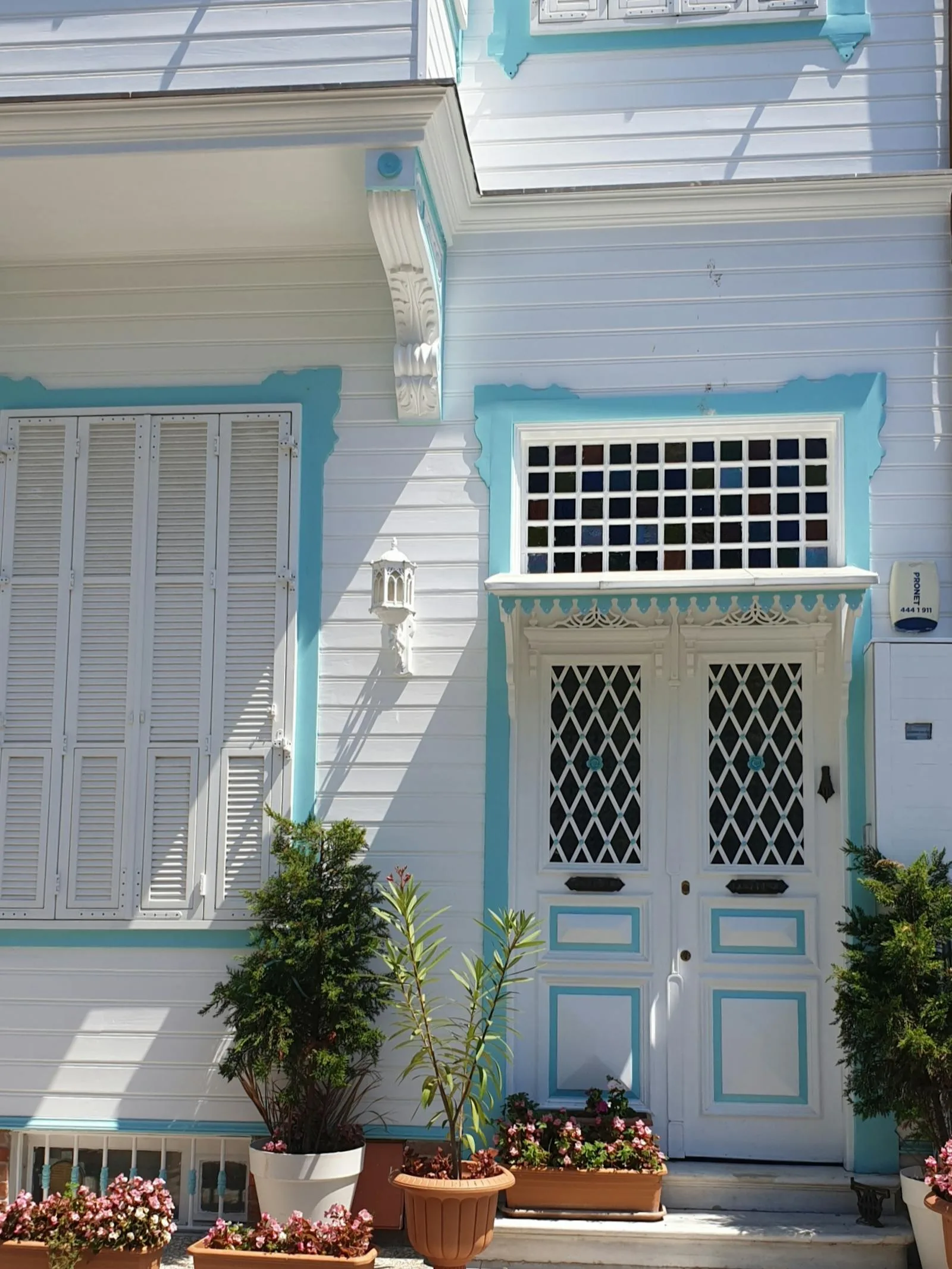 Turquoise front door with shutters, potted plants, and a bright exterior wall
