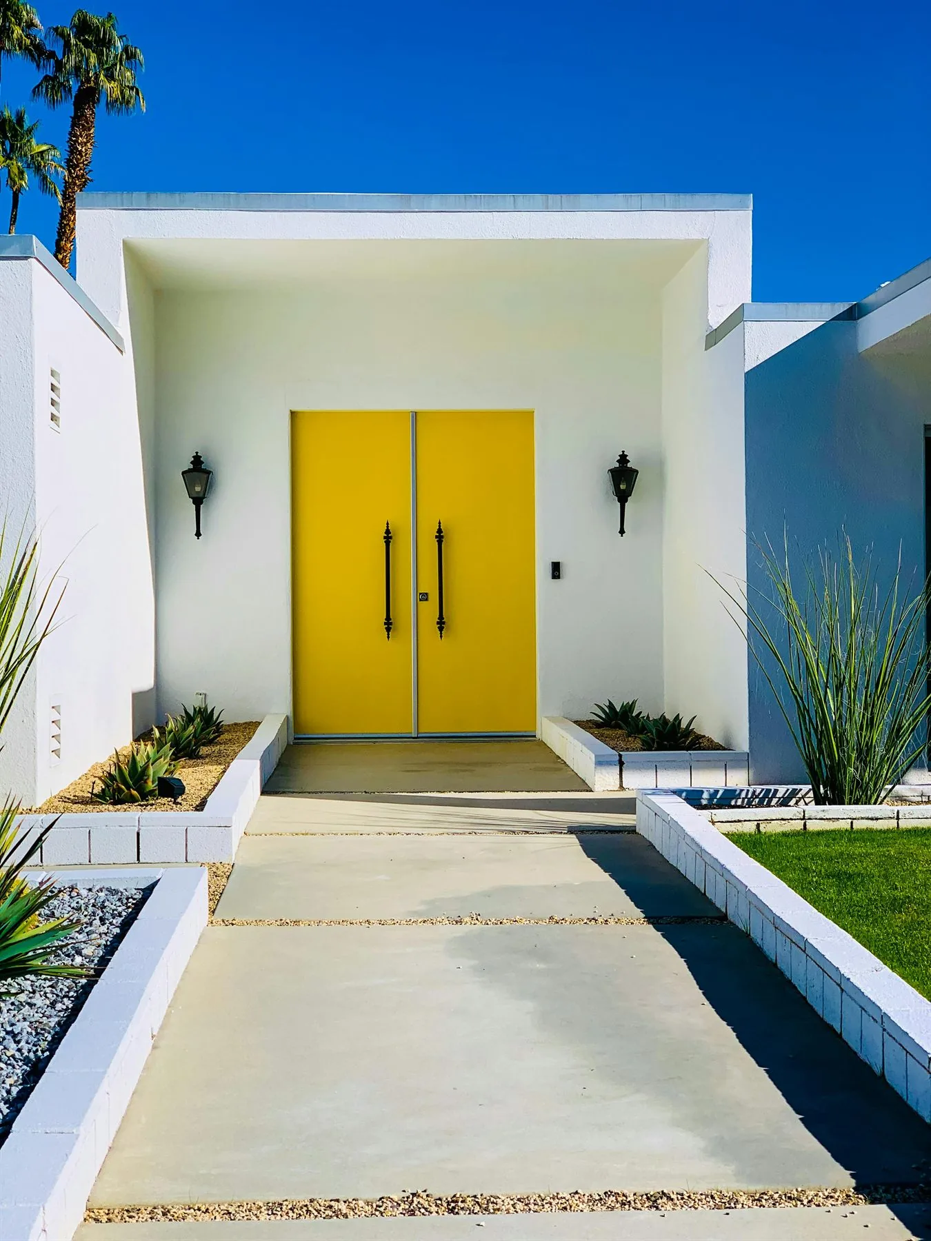 Bright yellow front doors on a white modern house with a simple symmetrical entry