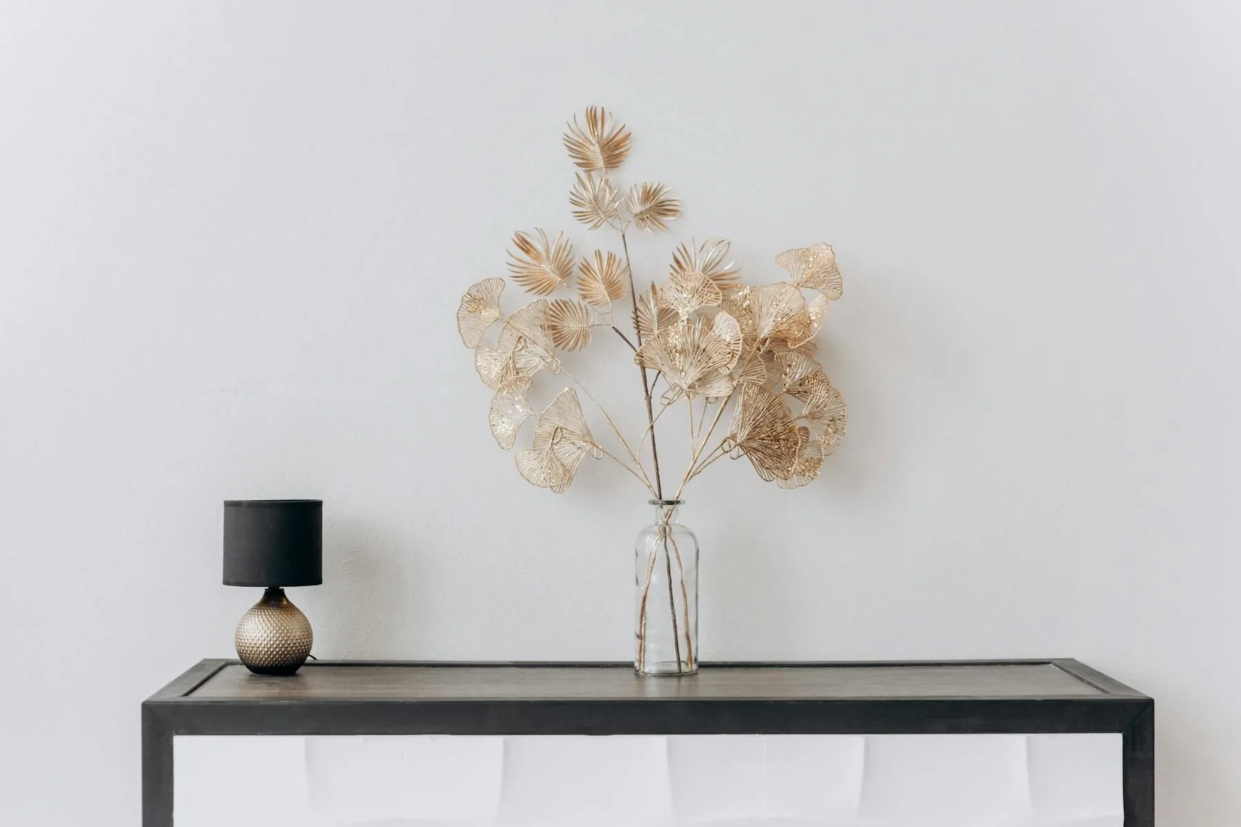 Minimal console with one lamp and one airy arrangement in a calm bright room