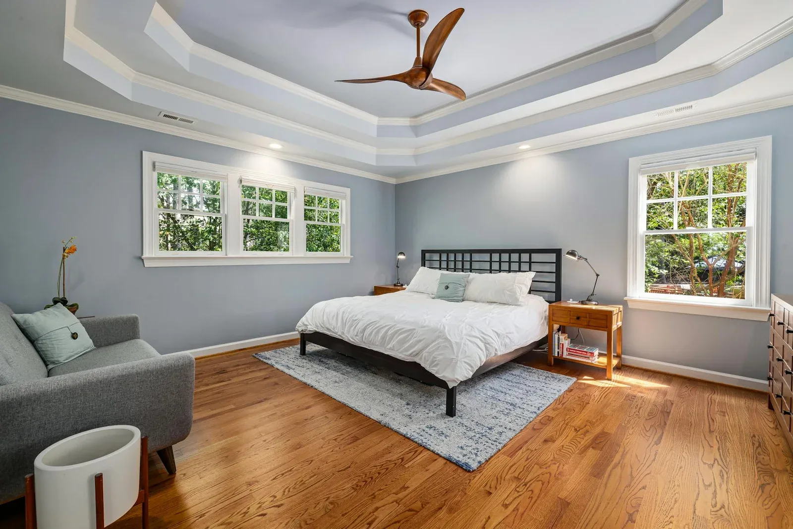 Bedroom with soft blue-green walls, warm wood floor, and quiet daylight