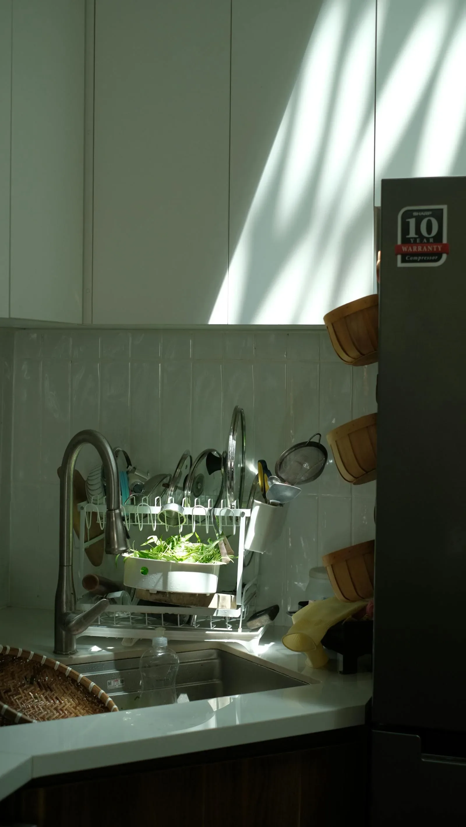Kitchen with muted green tile, soft wood, daylight, and a calmer natural palette