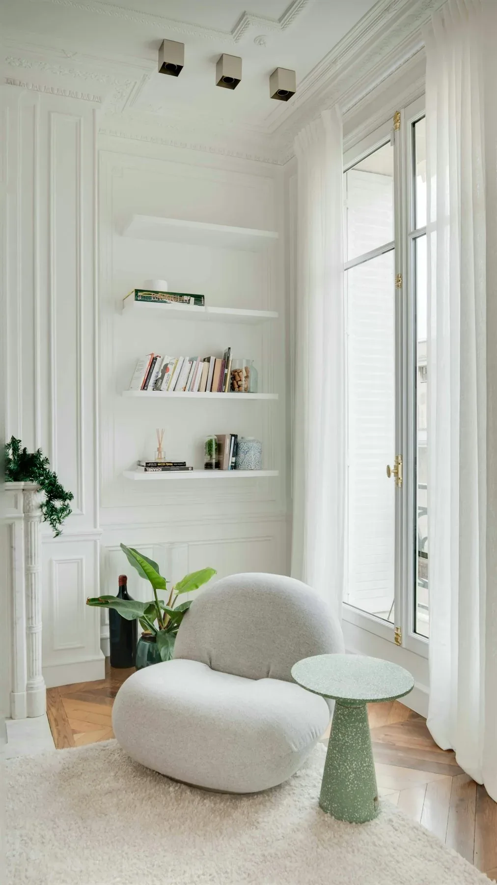 Bright white room with soft green plants on shelving and a calm natural palette