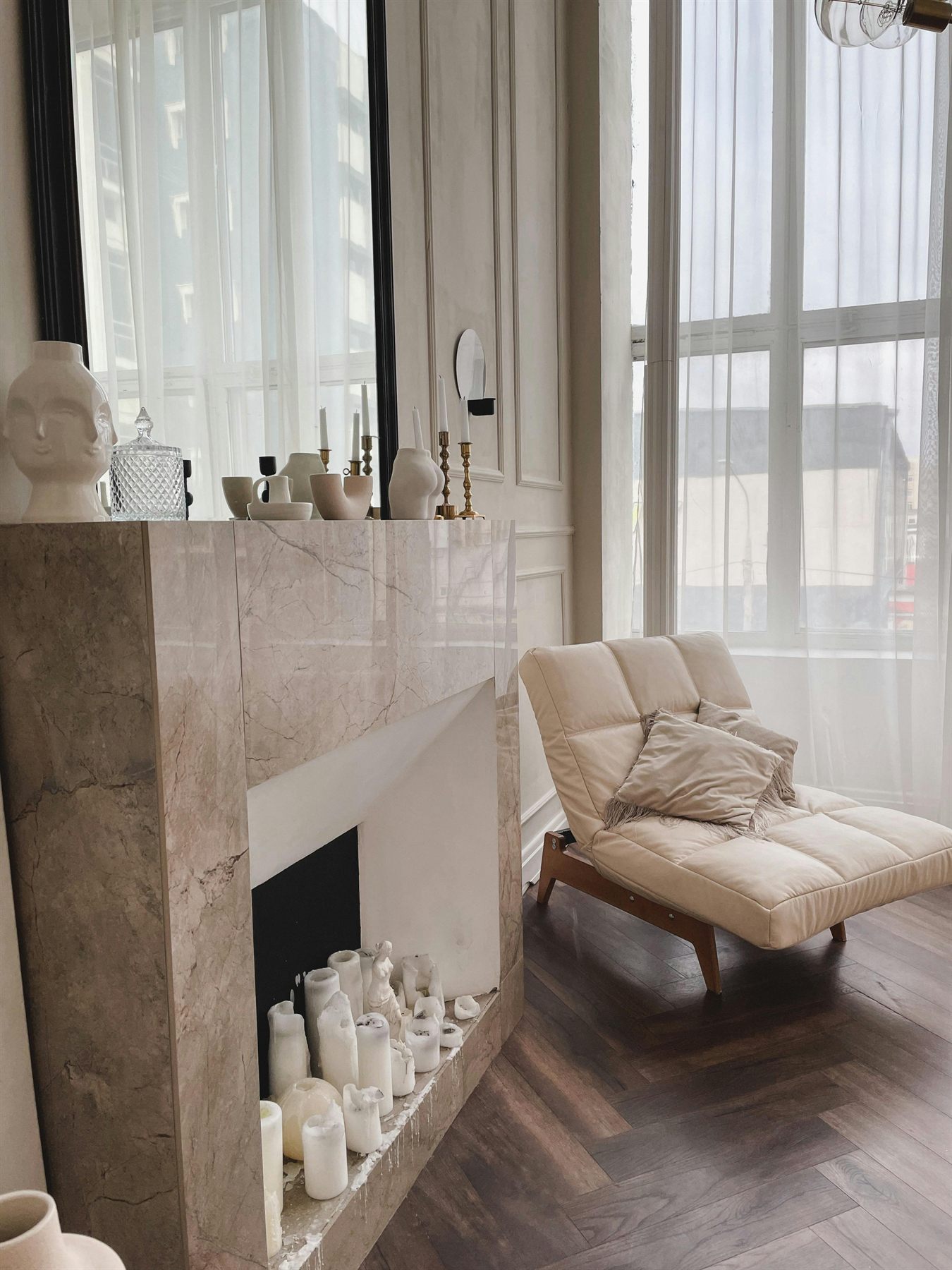 Warm neutral room with cream chair, fireplace, layered texture, and calmer styling