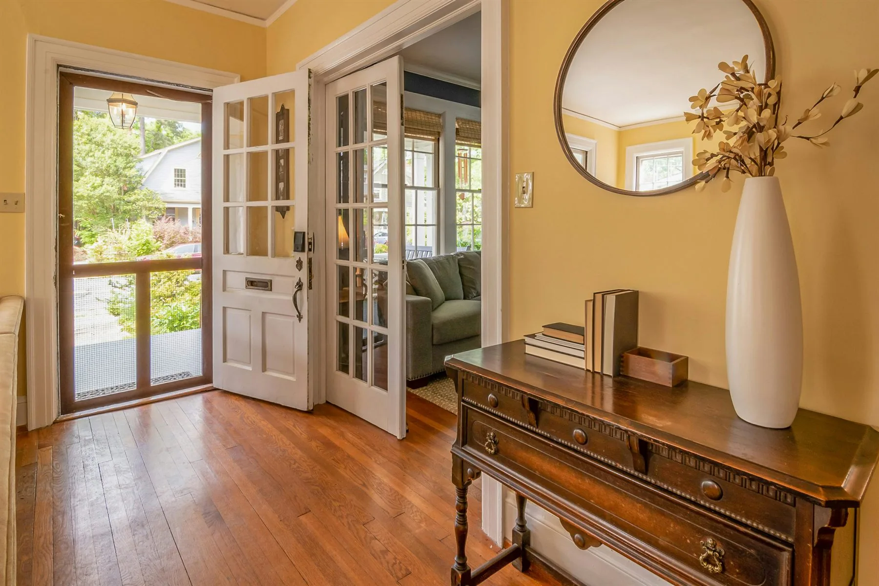 Round mirror above a warm dresser with simple styling and softer light