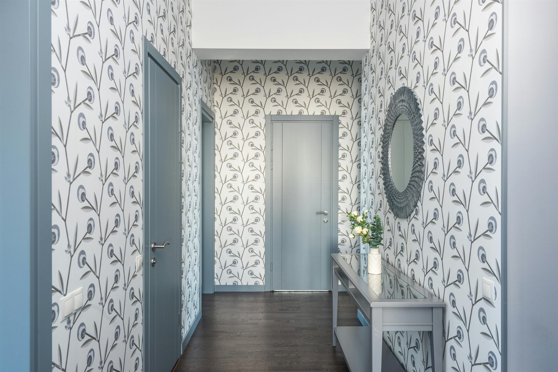 Entry hall with soft gray-blue doors, patterned wallpaper, and a narrow console table