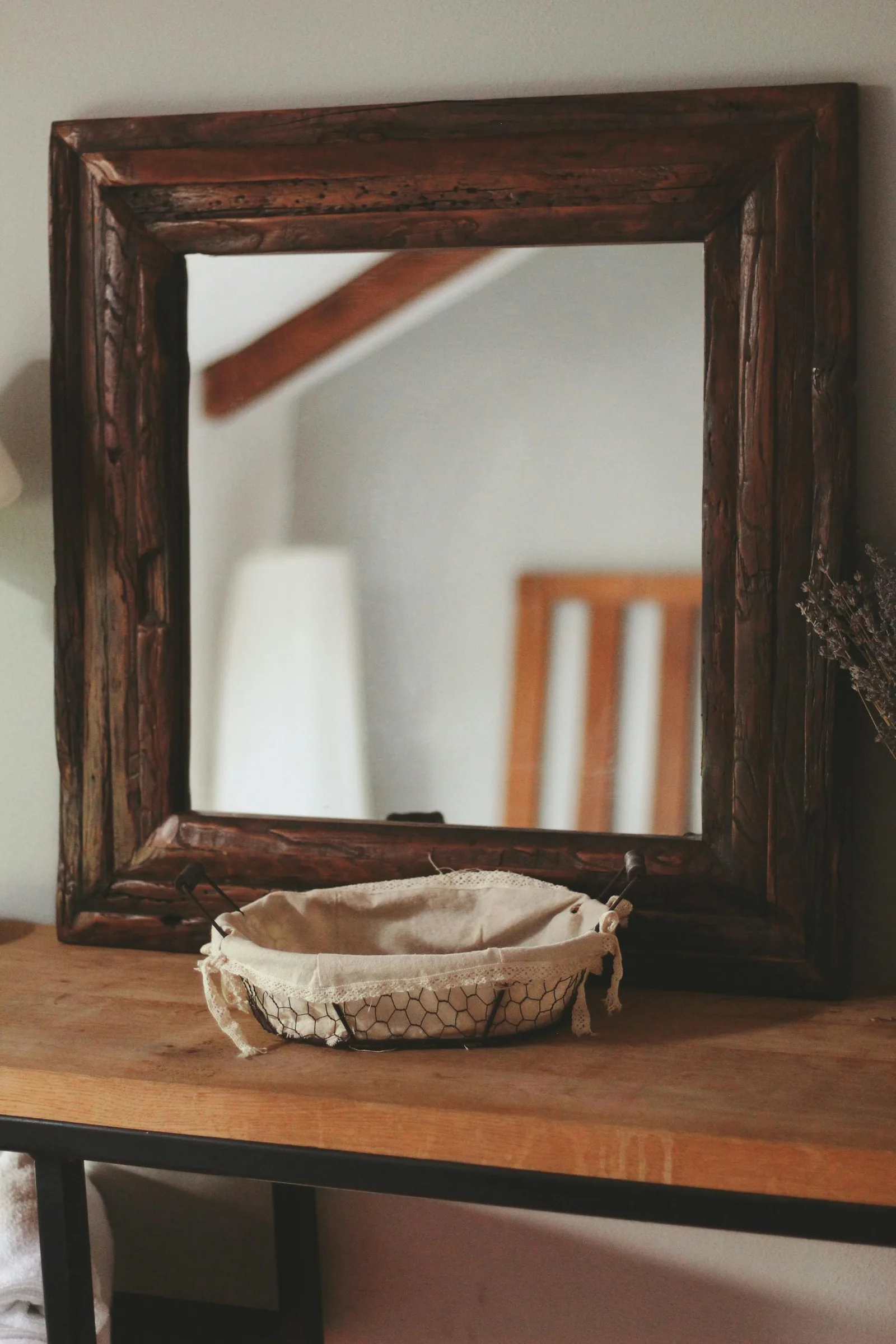 Warm wood framed mirror reflecting a soft lamp and quiet interior