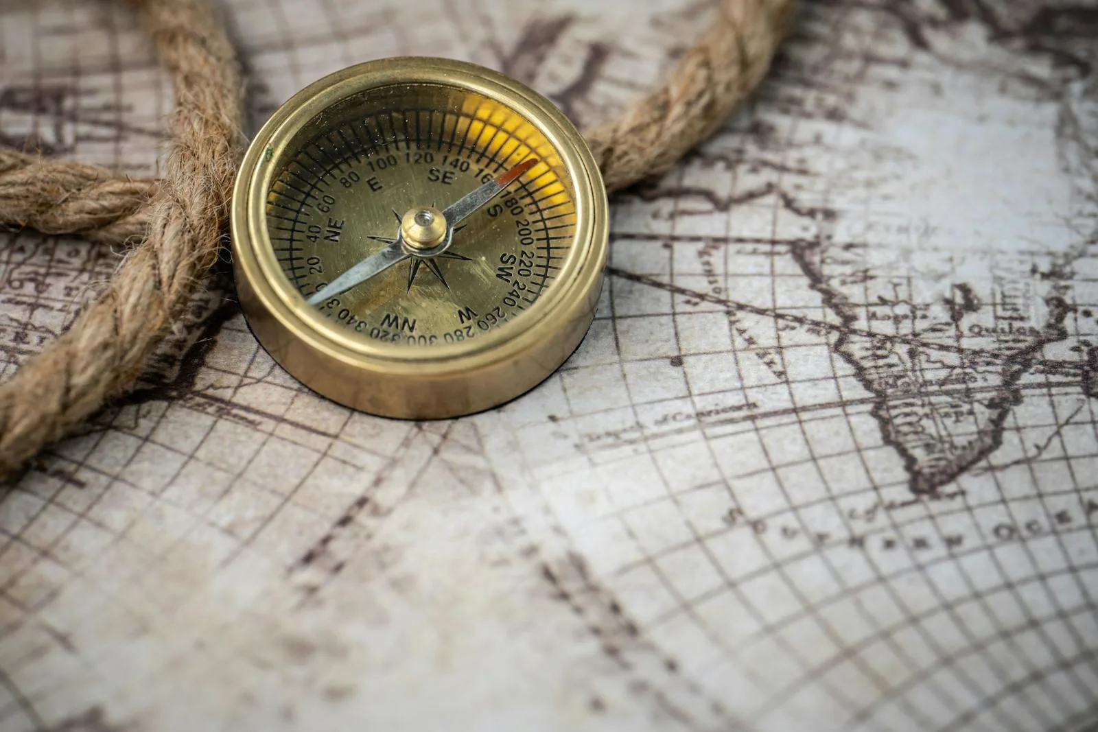 Brass compass on an old map with rope detail