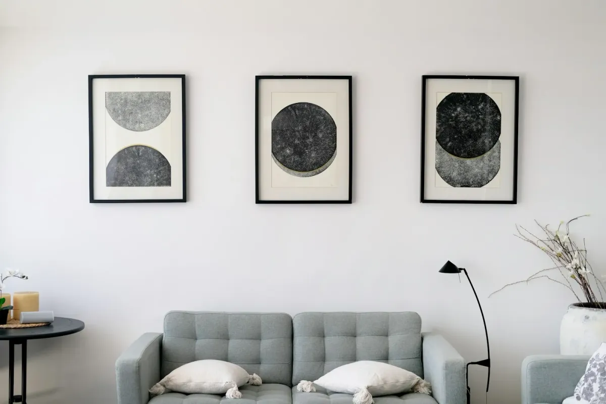 Living room with three abstract art pieces above a gray sofa