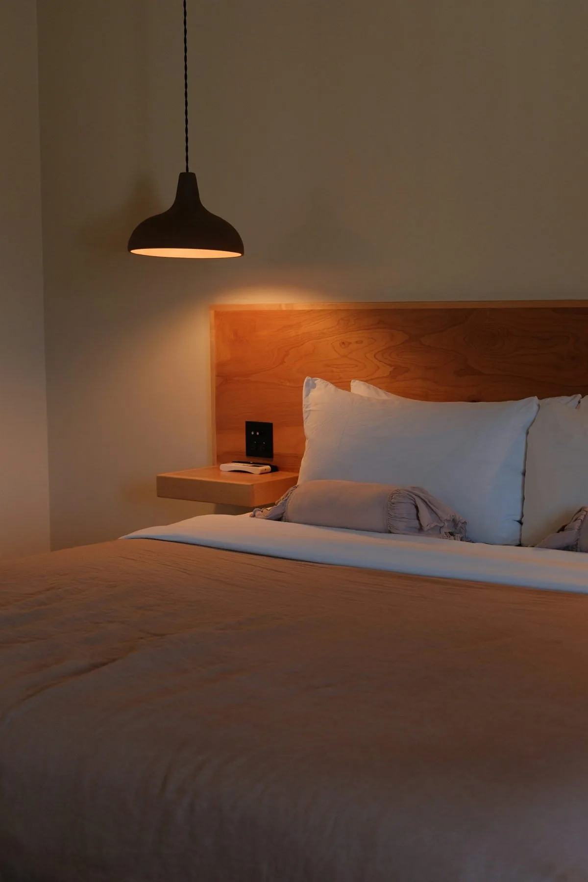Bedroom with a tall green paneled headboard wall, warm lamps, and a protected bed feel