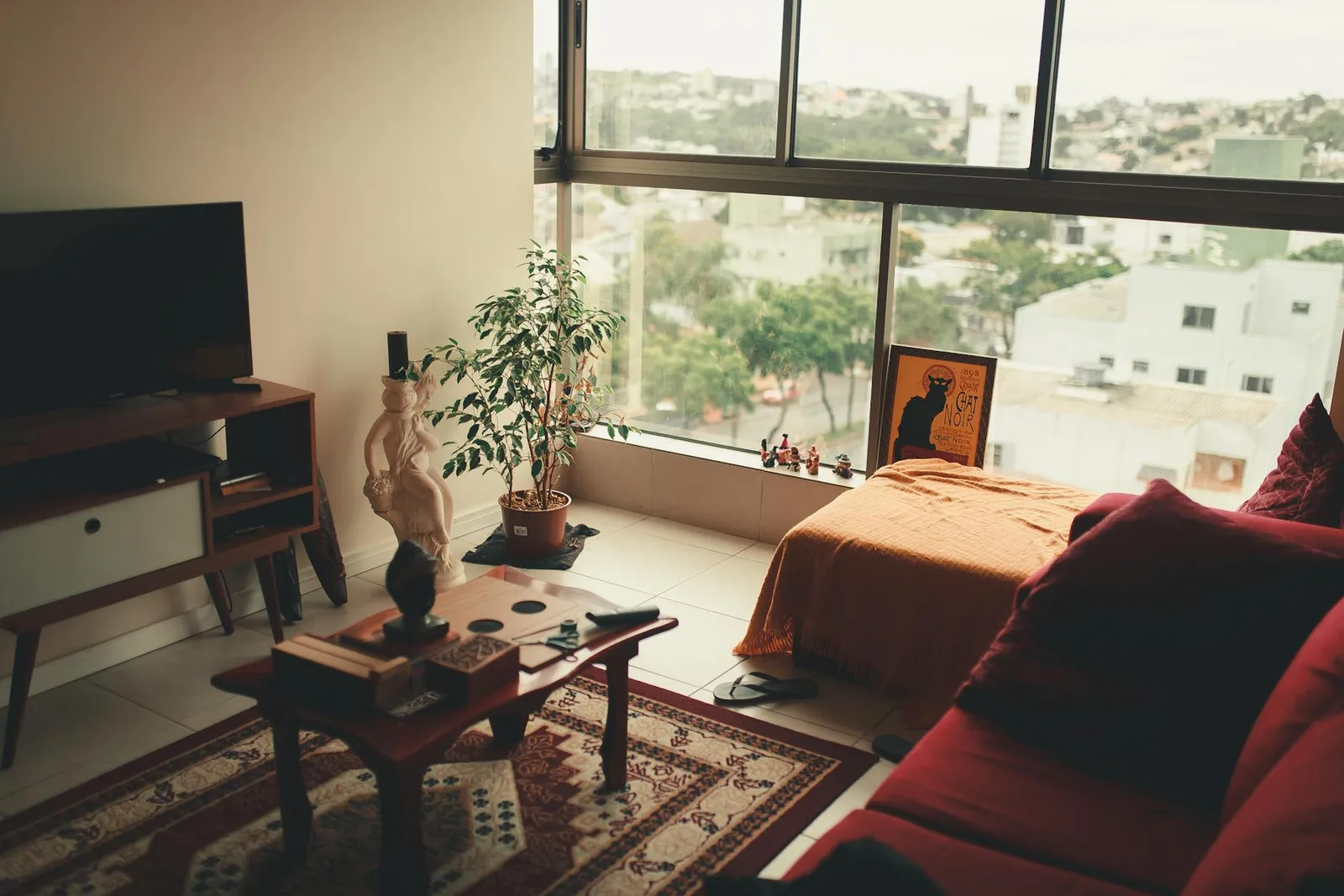 Small apartment bedroom area with a bed, sofa zone, window light, and compact room planning