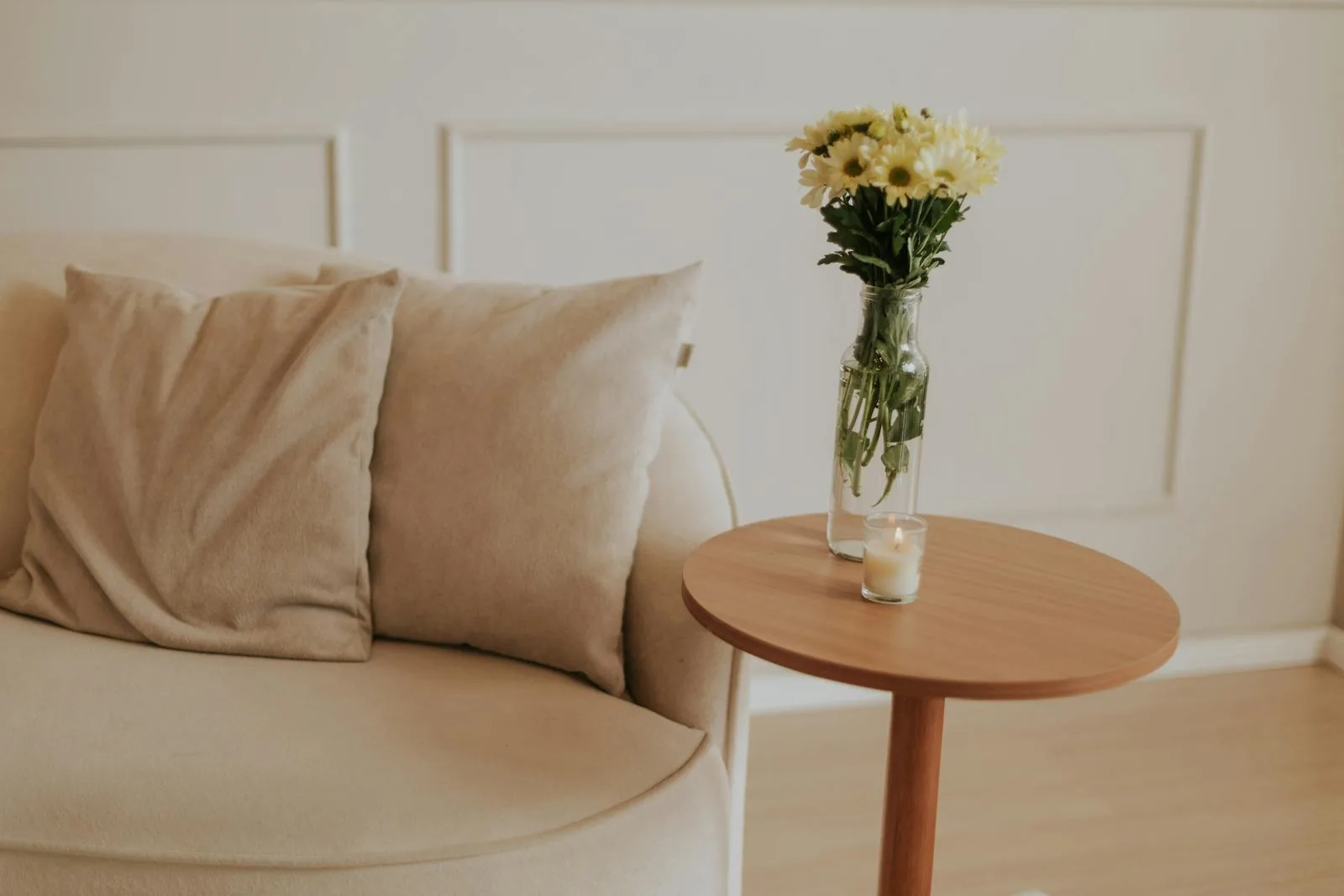 Soft beige seating corner with a small wood side table and a quiet understated arrangement