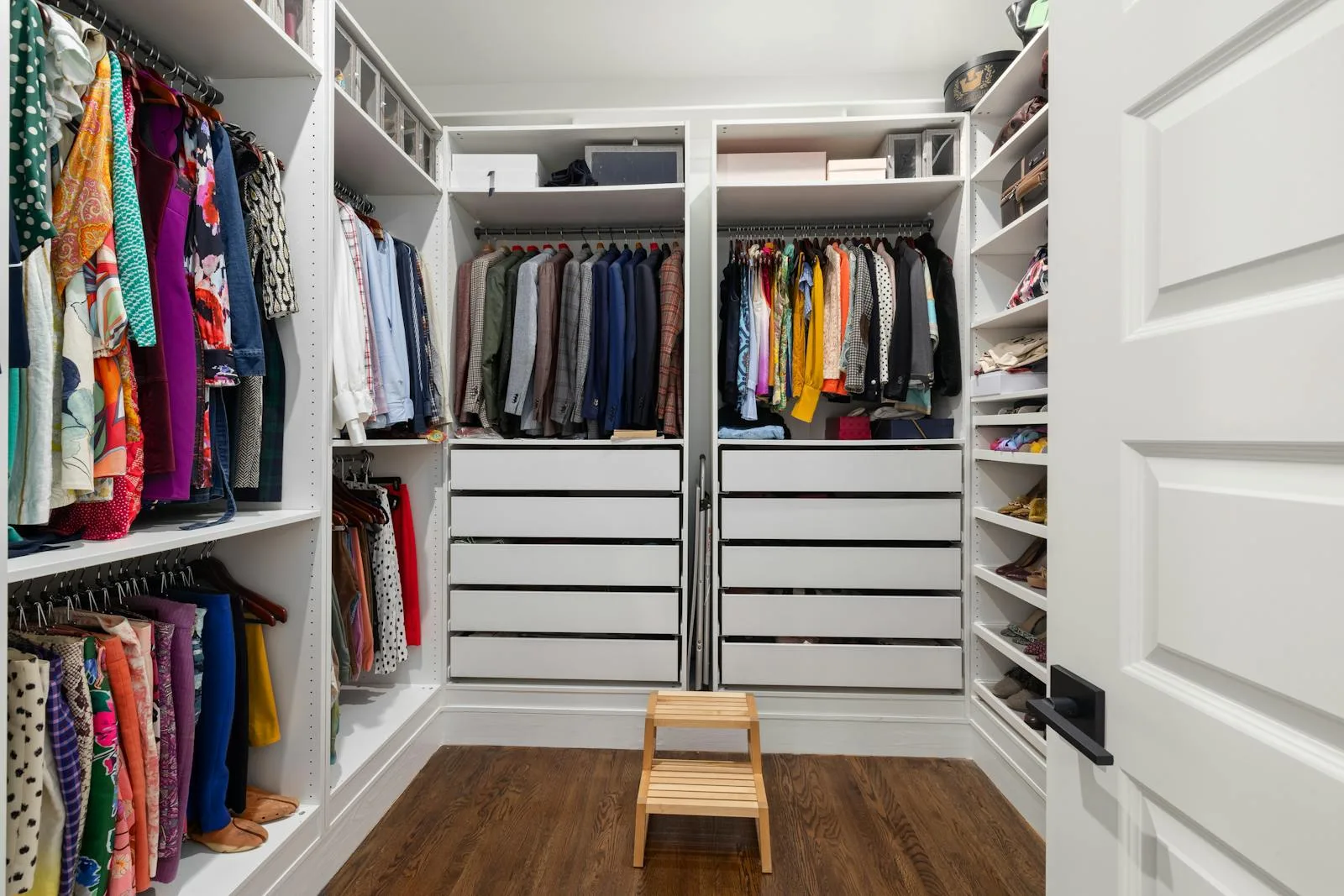 Walk-in wardrobe with hanging clothes, drawers, shelves, and a clear floor path