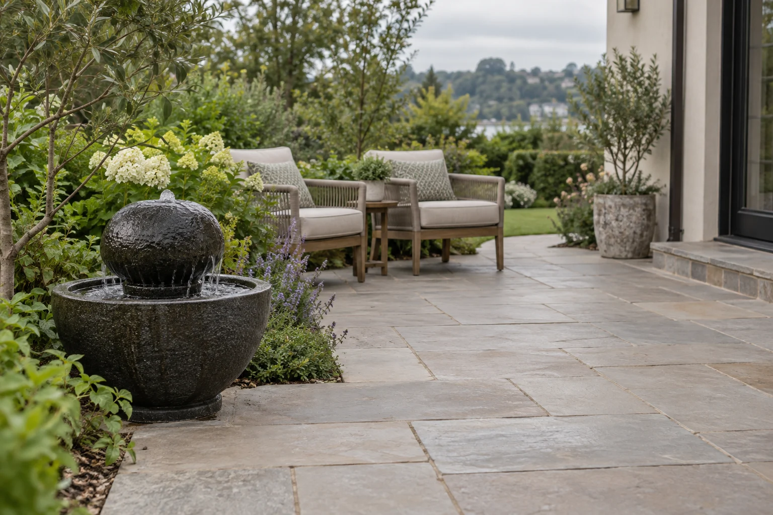 Small stone bubbling fountain in a contained basin beside a clear paved terrace